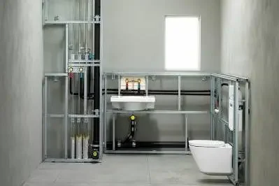 Badezimmerinstallation mit Toilette, Waschbecken und freiliegenden Rohren.