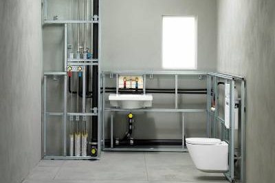 Badezimmerinstallation mit Toilette, Waschbecken und freiliegenden Rohren.